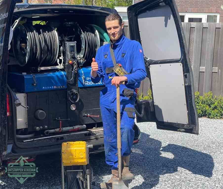 Een tevreden monteur met opgestoken duim naast de bestelbus, slim ingrijpen bespaart kosten bij een verstopte afvoer in Schiedam