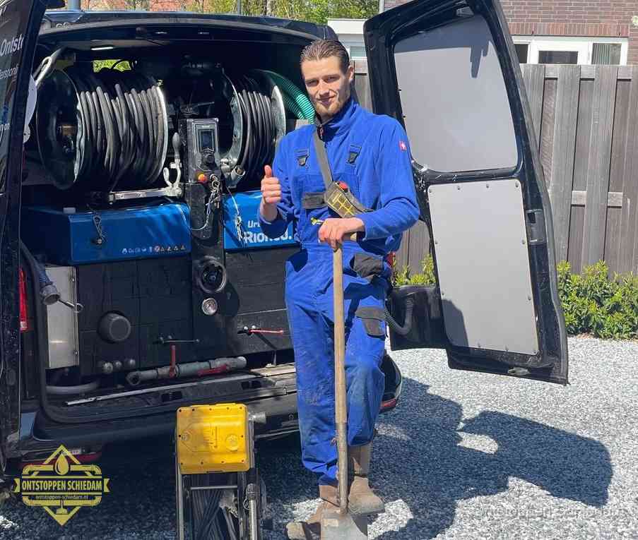 Een monteur bij de werkbus met grote hogedruk-slanghaspels, apparatuur voor hardnekkige afvoerverstoppingen in Schiedam