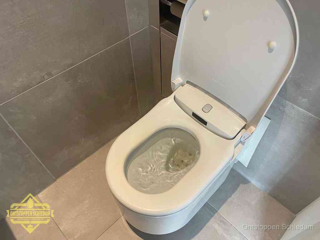 Een toiletpot vol troebel water met drijvend papier en restanten, de meest voorkomende oorzaak van een verstopte wc in Schiedam