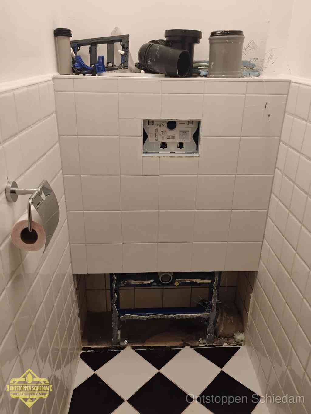 Een toiletruimte waar het hangtoilet en de inbouwreservoir-onderdelen zijn vrijgelegd voor onderhoud, periodiek nazicht voorkomt een wc-verstopping in Schiedam