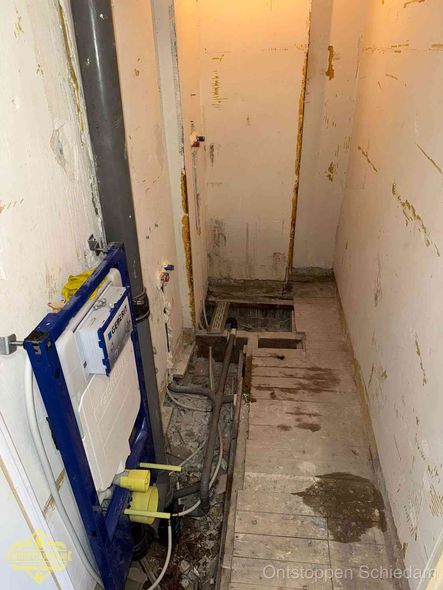 Een opgebroken toiletruimte tijdens renovatie met een Geberit inbouwreservoir en blootliggende oude afvoerleidingen, typisch voor oudere woningen in Schiedam